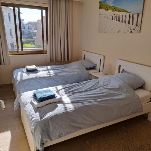 two beds in a bedroom with a window at Appartement Residentie Amadeus met garage-lift in Sint-Idesbald