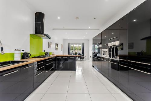 a large kitchen with black and green cabinets at Stunning 4 Bed House - Sleeps 12 in Cheltenham