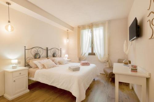 een witte slaapkamer met een groot bed en een bureau bij Il Piccolo Borgo for 7 guests in Certaldo
