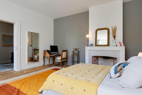 a white bedroom with a bed and a fireplace at La Papautiere in Carignan