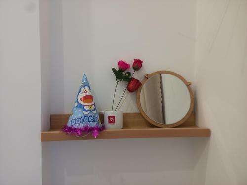 a shelf with a mirror and flowers and a candle at Chang Homestay in Quy Nhon
