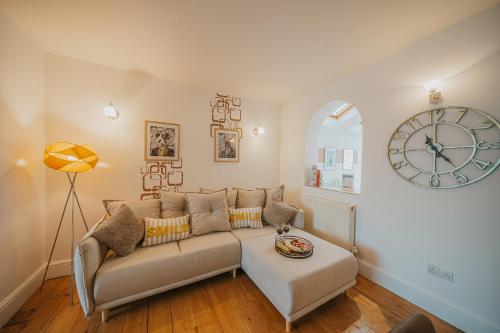 a living room with a couch and a clock on the wall at Cotswolds- Homely 2 bed house with garden, WiFi - Esho Stays in Cirencester