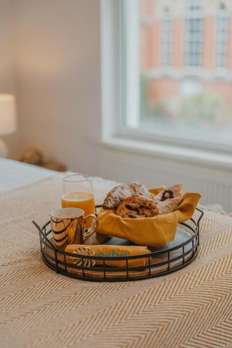 a tray with a plate of food and two glasses of orange juice at Cotswolds- Homely 2 bed house with garden, WiFi - Esho Stays in Cirencester