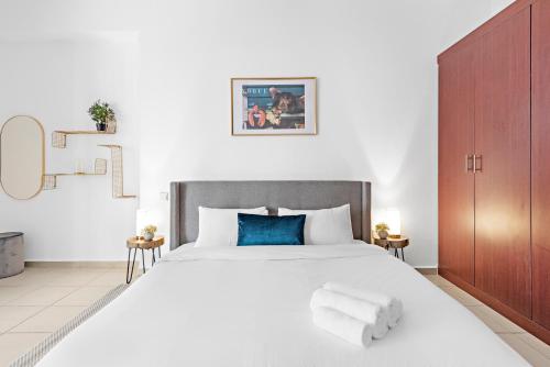 um quarto branco com uma cama grande e almofadas azuis em Serene Studio APT Rimal 3 JBR em Dubai