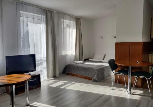 sypialnia z łóżkiem, telewizorem i stołem w obiekcie Warsaw Apartments Magnolie w Warszawie