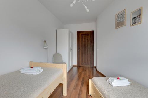 a bedroom with two beds and a wooden floor at Apartment Brzeźno Beach by TriApart in Gdańsk