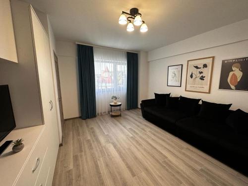 a living room with a black couch and a window at Cozy Studios in Suceava in Suceava