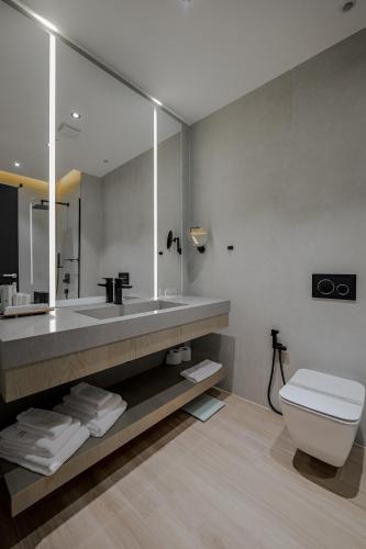 a bathroom with a sink and a toilet and a mirror at Hotel Uji Ftohte Tepelene in Tepelenë