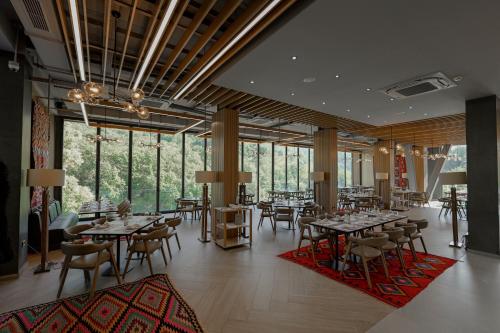 a restaurant with tables and chairs and large windows at Hotel Uji Ftohte Tepelene in Tepelenë