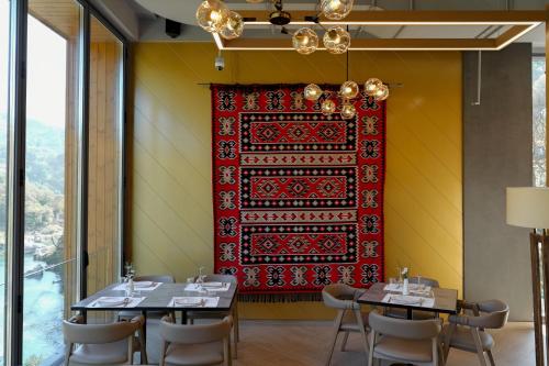 a dining room with two tables and a red rug on the wall at Hotel Uji Ftohte Tepelene in Tepelenë