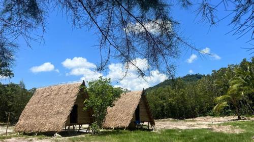 a house with a straw roof on a field at Green smile camping and private beach in Krabi