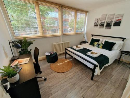 a bedroom with a bed and a desk and windows at 2 Bedroom flat in great location! in London