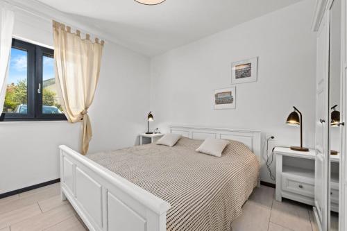 a white bedroom with a bed and a window at Charming apartment Emilija in Pula