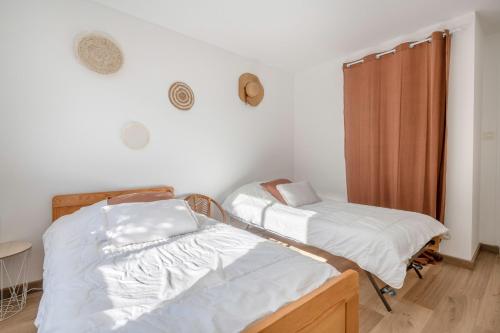 two beds in a room with white walls at Préfailles - Maison 6 Pers - 200m des plages in Préfailles