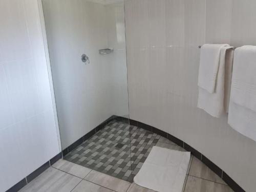 a bathroom with a shower with a glass door at Mmelesi Lodge in Maseru