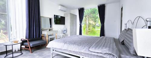 a bedroom with a bed and a desk and a window at Du Lịch Lâm Hà - Hồ Gia Trang Villas in Lam Ha