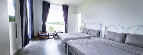 a bedroom with two beds and a large window at Du Lịch Lâm Hà - Hồ Gia Trang Villas in Lam Ha