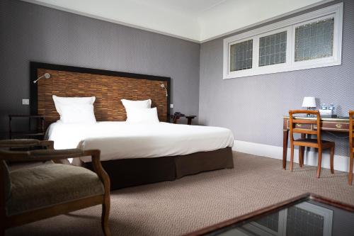 a hotel room with a large bed and a desk at Le Grand Hotel in Tours