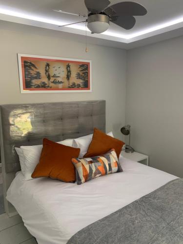 een slaapkamer met een bed met witte lakens en oranje kussens bij Footprints Self Catering Solar No Loadshedding in Lanseria