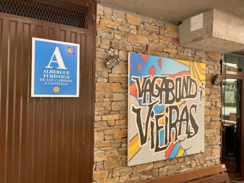 a building with two posters on a stone wall at Vagabond Vieiras Beds & Dinner Albergue in La Portela de Valcarce