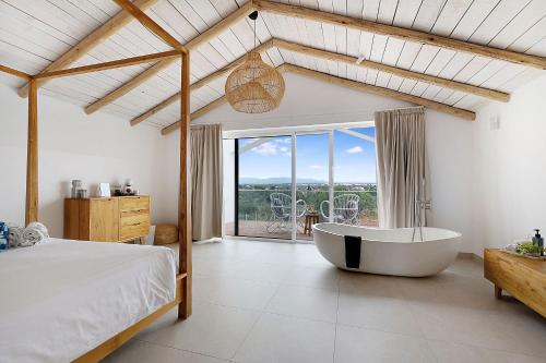a bedroom with a bed and a tub in a room at Quinta do Ourives in Carvoeiro