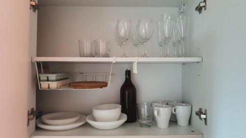 a cupboard with glasses and bowls and a bottle of wine at The New Villa at Sea Residences in Manila