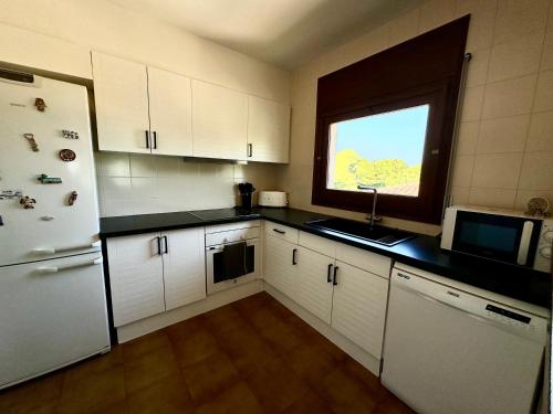 a kitchen with a white refrigerator and a window at Melis Mar - Apartamento con vistas en Pals in Pals