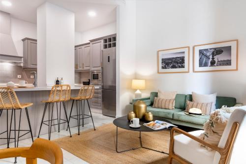 ein Wohnzimmer und eine Küche mit einem Sofa und einem Tisch in der Unterkunft MonKeys Apartments Luxury Puerta de la Maestranza in Sevilla