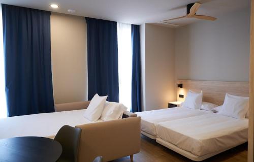 una habitación de hotel con 2 camas y una silla en Hotel-Apartamentos Primus Suites en Valencia