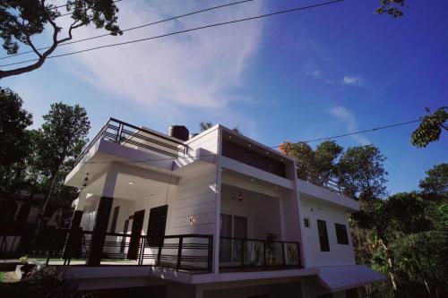 a white house with a balcony on top of it at Vaishnavam Double Bedroom Villa in Thekkady