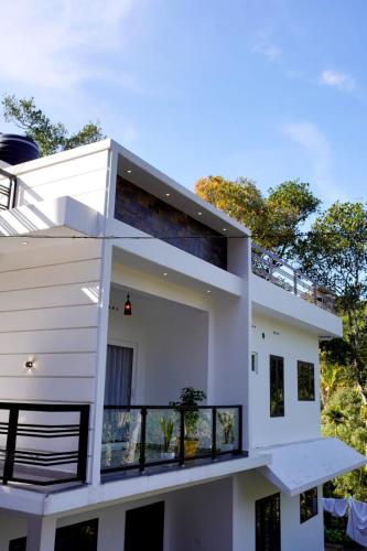 a large white house with a balcony at Vaishnavam Double Bedroom Villa in Thekkady