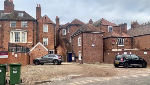 two cars parked in front of a brick building at Upstairs at 33 - Self check in boutique accommodation in Worcester Centre in Worcester