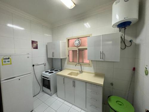 a small kitchen with white cabinets and a green stool at Al Fanar Palace 2 in Riyadh