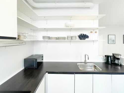 a kitchen with white cabinets and a black counter top at Beautiful One-Bedroom Apartment in CPH City in Copenhagen