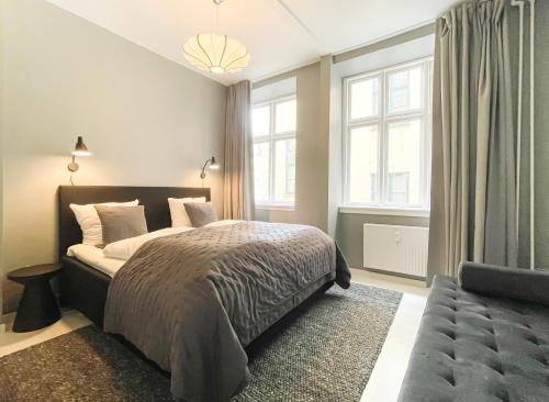 een slaapkamer met een bed, een bank en ramen bij Beautiful One-Bedroom Flat in CPH City in Kopenhagen