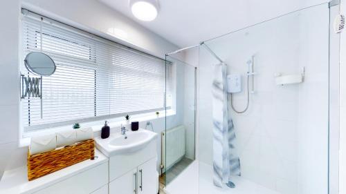 a white bathroom with a sink and a shower at Stunning Ranworth House Sleeps 5 in Bedford