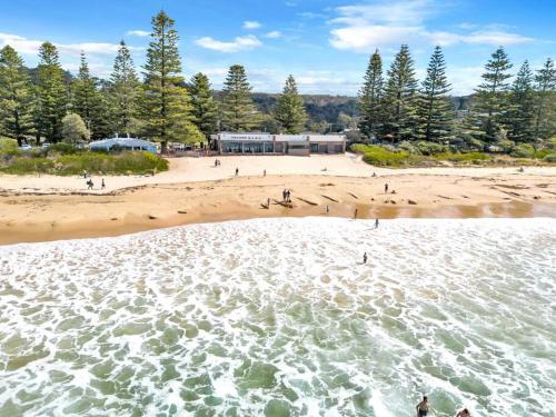 an aerial view of a beach with people in the water at Cabin Getaway in Tathra in Tathra