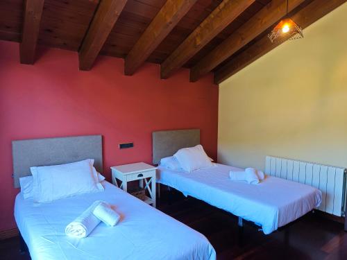 two beds in a room with a red wall at Els Tres Sols in Camprodon