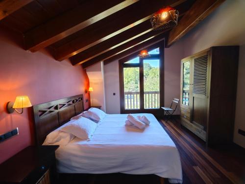 a bedroom with a large bed with white sheets and a window at Els Tres Sols in Camprodon