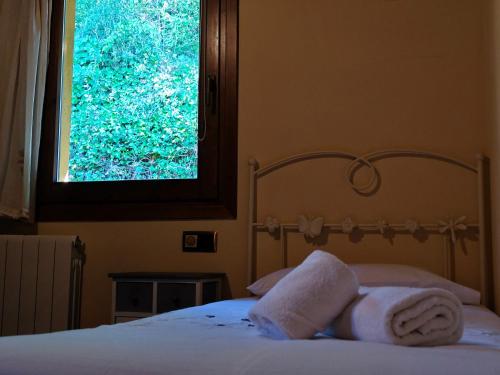 a bedroom with a bed and a window with towels at Els Tres Sols in Camprodon