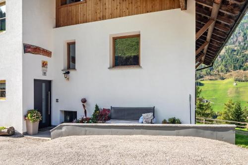 a white house with a bench in the courtyard at Glocklechnhof Sonnenschein in Cadipietra
