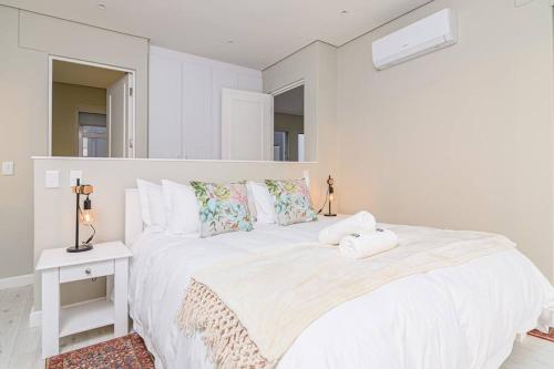 a white bedroom with a large white bed with pillows at Beachfront Villa in Swakopmund