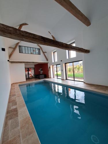 una grande piscina con acqua blu in una casa di Gîte du Plantagenêt - Piscine intérieure privative a Rouez