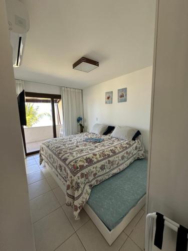 1 dormitorio con cama y vistas a un balcón en Ekoara Residence bangalô 07, en Porto de Galinhas