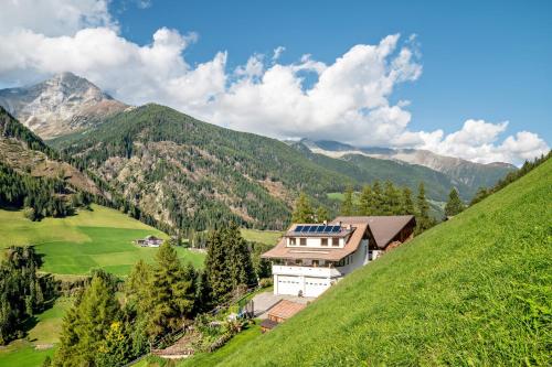 a house on a hill with mountains in the background at Glocklechnhof Sonnenschein in Cadipietra