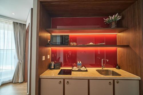 a kitchen with a sink and a red wall at Mandala Casa del Sol Mũi Né in Mui Ne