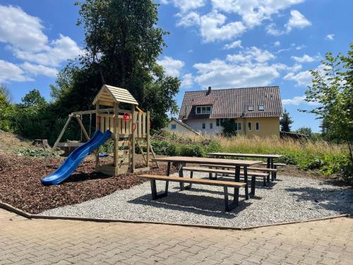 un parque infantil con tobogán y 2 bancos en Ferienhaus Bodensee - by Heinke Wohnraum en Oberteuringen