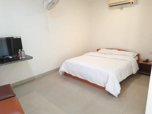 a white bedroom with a bed and a television at Srushti Farms Resort in Vasind
