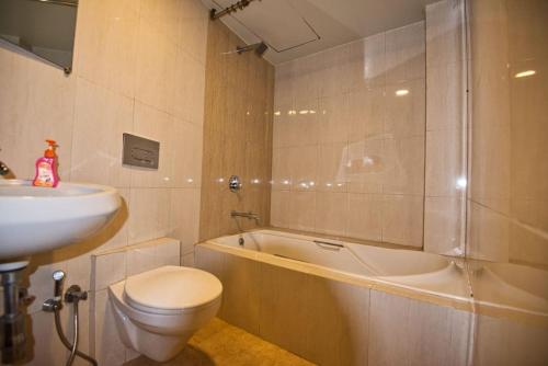 a bathroom with a sink and a toilet and a tub at Srushti Farms Resort in Vasind