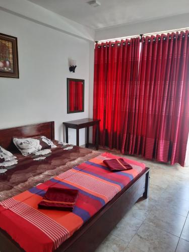 a bedroom with a large bed with red curtains at White Surfing Beach Resort in Unawatuna